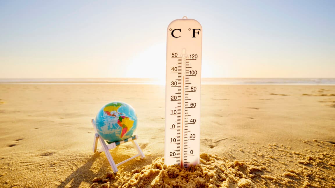 a sandy beach with a globe balanced in a beach chair next to an oversized thermometer showing high temperatures. (via arstechnica.com)